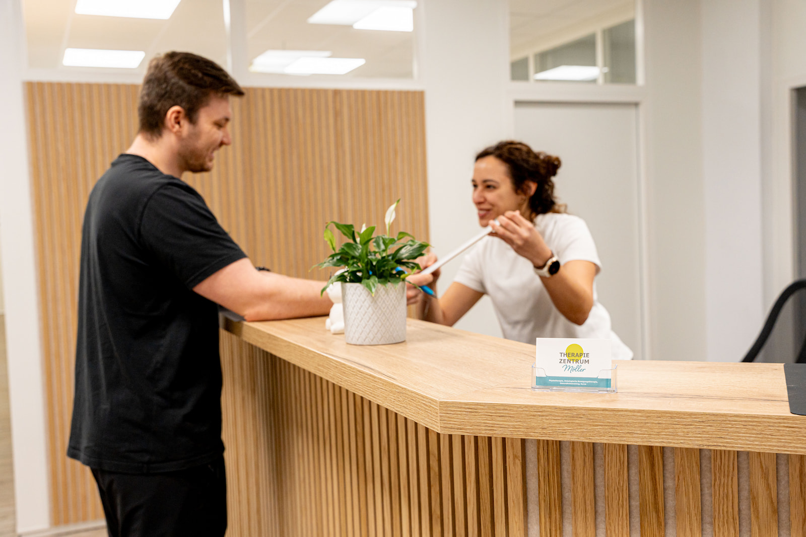 Patient meldet sich am Empfang für Physiotherapie ohne Rezept im modernen Therapiezentrum