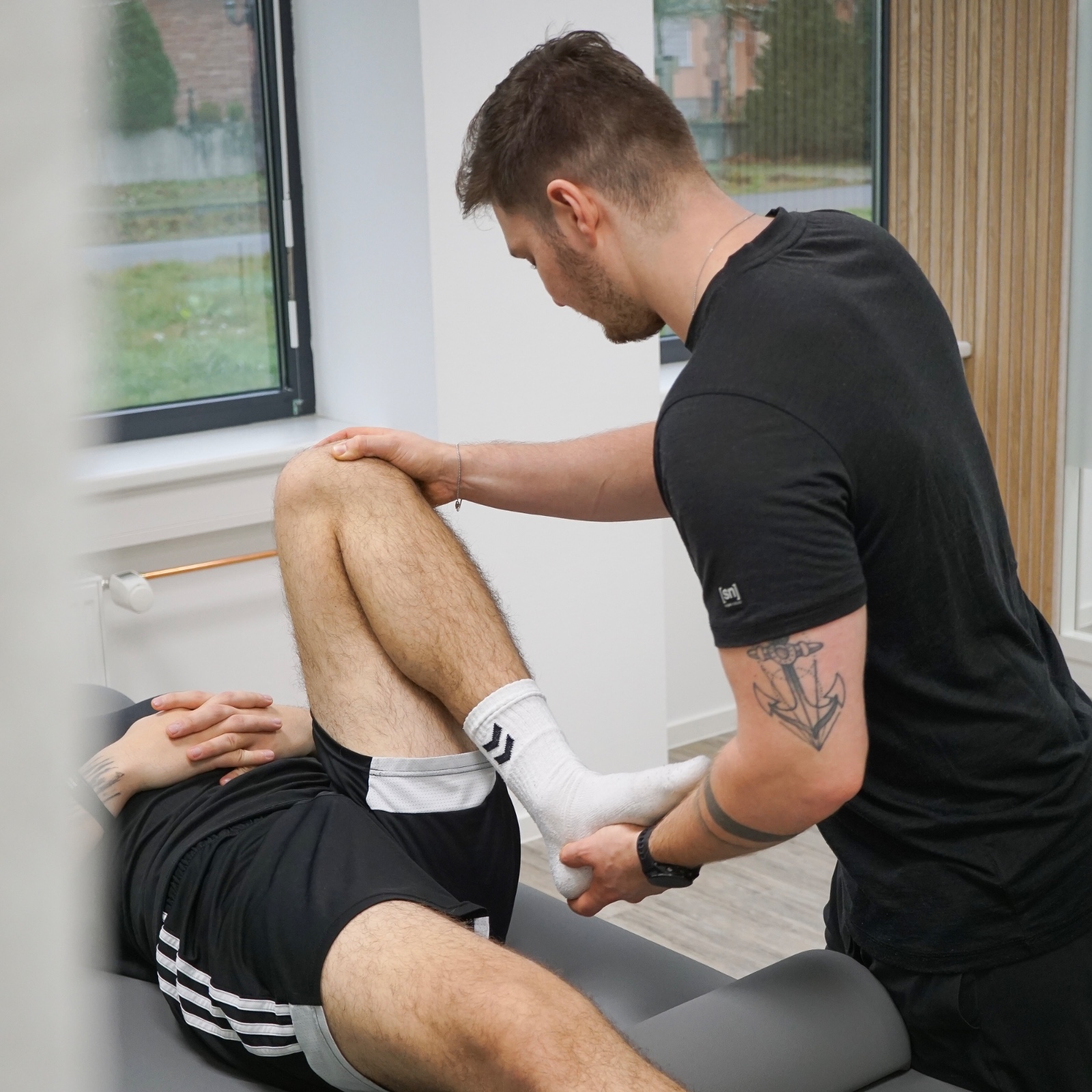Physiotherapeut mobilisiert das Knie eines Patienten während einer Behandlung. Zusätzliche Behandlungszeit kann helfen, Therapieerfolge zu verbessern.