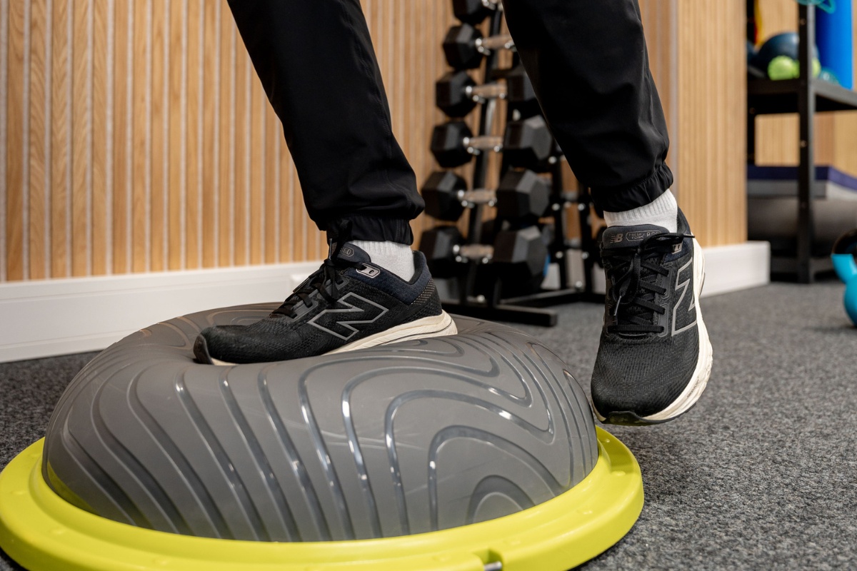 Patient trainiert Gleichgewicht auf einem Balance Board während einer physiotherapeutischen Behandlung