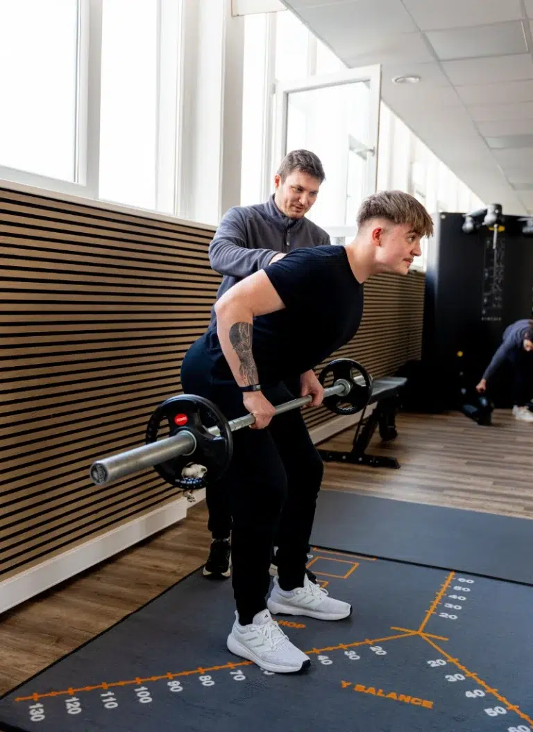 Patient beim Krafttraining mit Langhantel unter therapeutischer Anleitung im Therapiezentrum Möller in Kandel