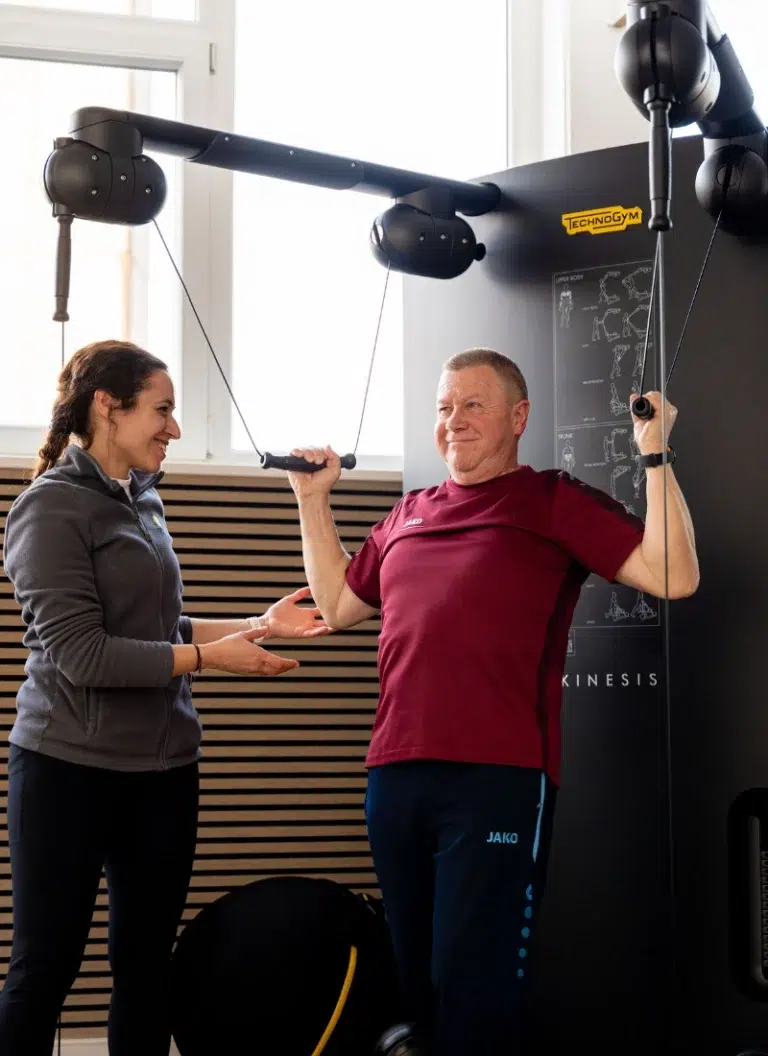 Therapeut begleitet einen Patienten beim Gesundheitstraining an einem Trainingsgerät im Therapiezentrum Möller in Kandel