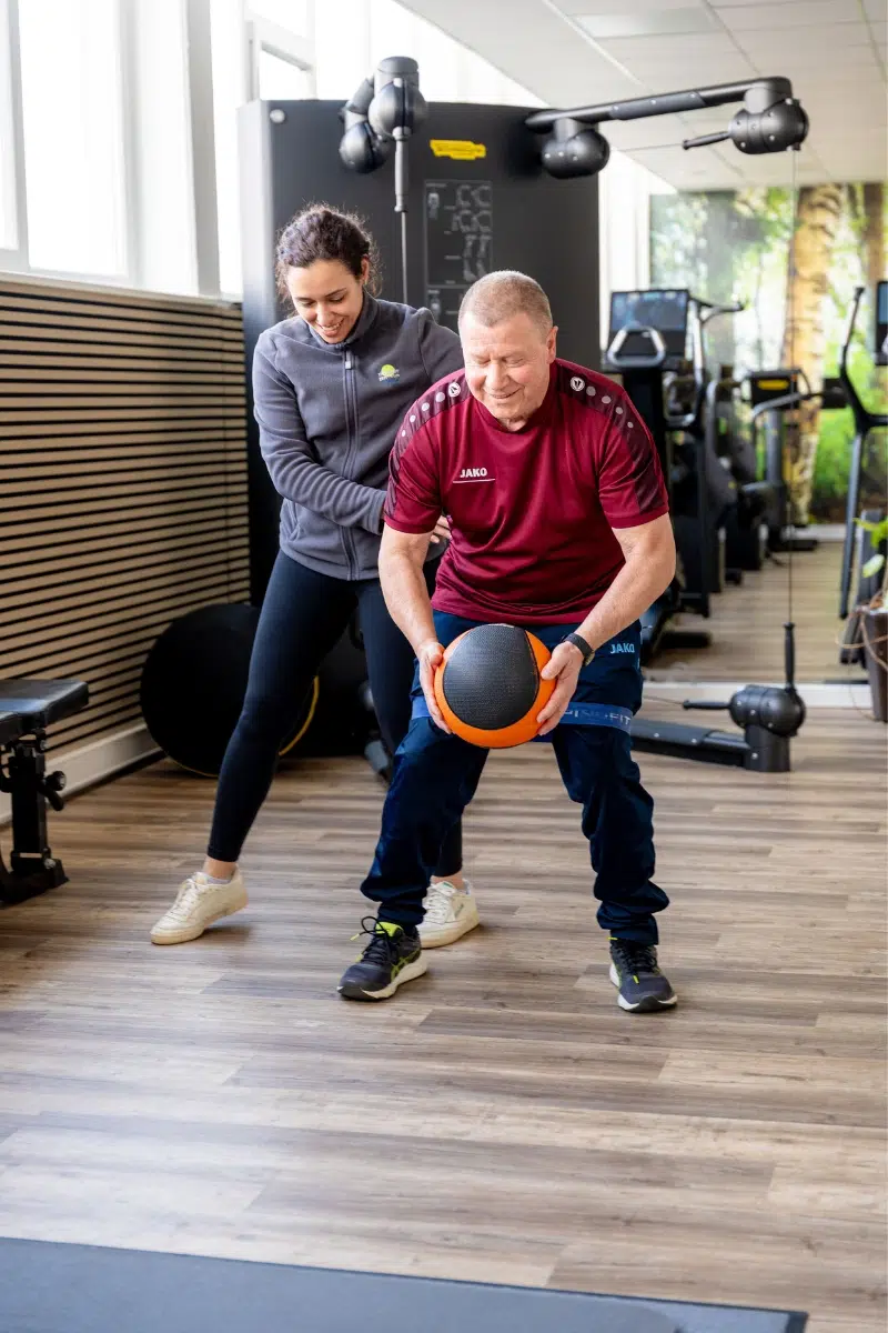 Therapeutin begleitet einen Patienten bei einer Bewegungsübung mit einem Medizinball im Therapiezentrum Möller in Kandel